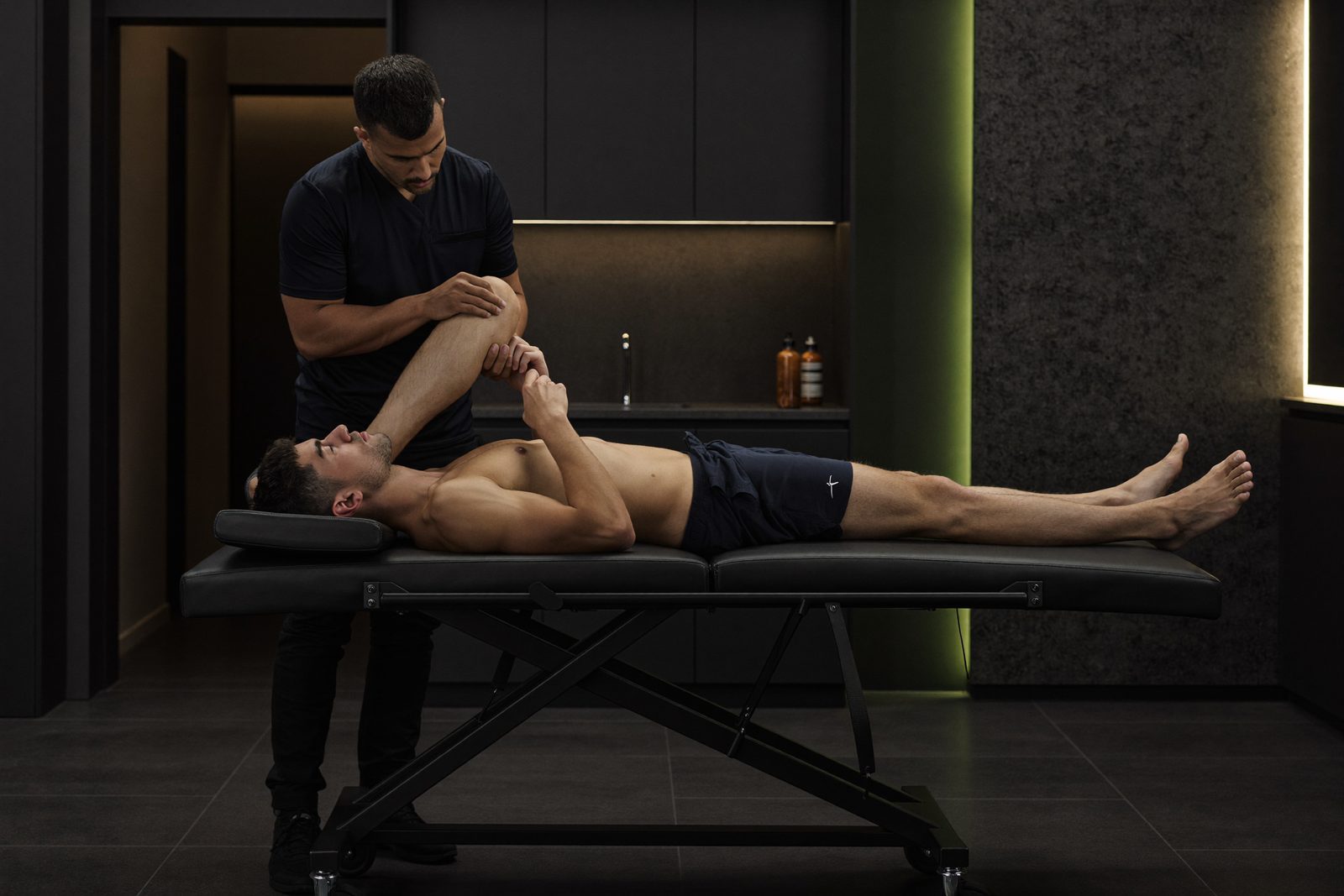 Fisioterapeuta valorando la rodilla de un deportista en un box de tratamiento